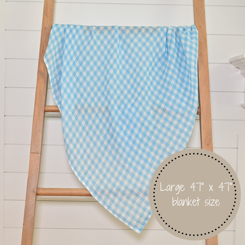 The Classic Comfort Blue Gingham 100% Muslin Cotton Swaddle Blanket - 47" x 47" beautifully displayed on a decorative ladder, infusing a sense of timeless elegance into any nursery or room.