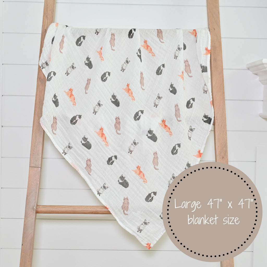 The Cat Prints Muslin Swaddle Baby Blanket - 47" x 47" elegantly displayed on a decorative ladder, adding a touch of style to any nursery or room.