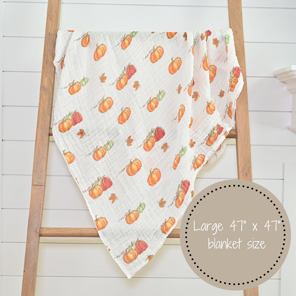 The Pumpkin Muslin Swaddle Blanket - 47" x 47" elegantly displayed on a decorative ladder, infusing your nursery or room with seasonal warmth and style.