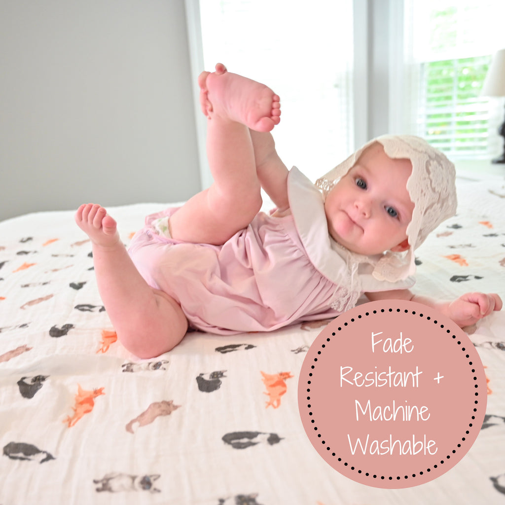 A baby girl in a yoga pose on the Cat Prints Muslin Swaddle Baby Blanket - 47" x 47", demonstrating both flexibility and comfort on this adorable blanket.