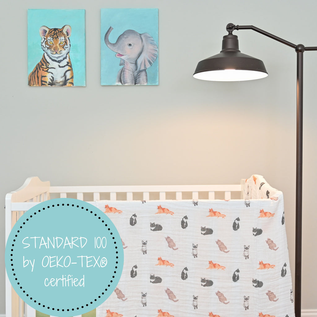 The Cat Prints Muslin Swaddle Baby Blanket - 47" x 47" beautifully hung on a crib, adding charm and coziness to the baby's nursery.
