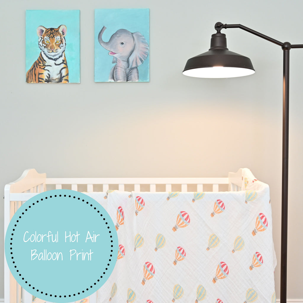 The Up, Up, and Away 100% Muslin Cotton Swaddle Blanket - 47" x 47" gracefully draped on a crib, infusing a sense of whimsical adventure into the nursery.